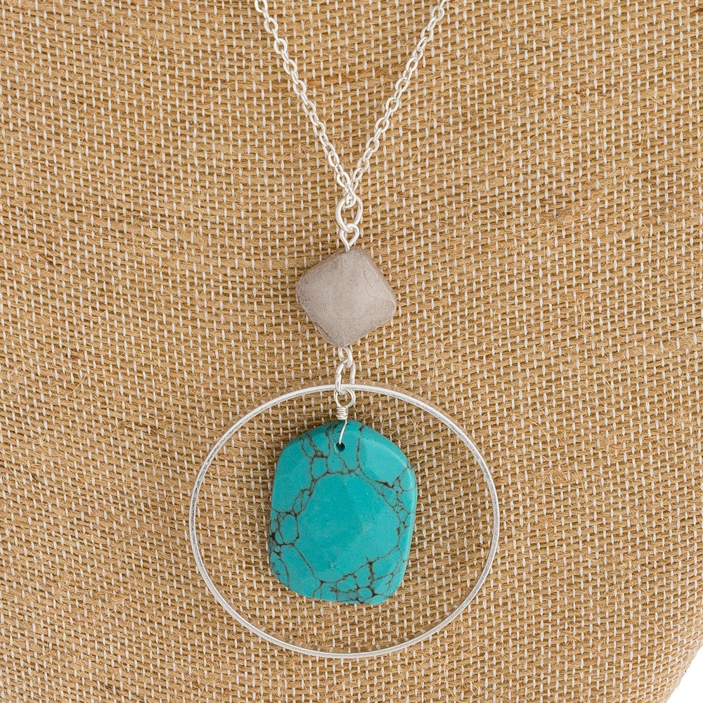 Long cable chain necklace featuring a circular metal pendant with a natural stone inspired center detail and a resin accent. Pendant approximately 3". Approximately 36" in length overall