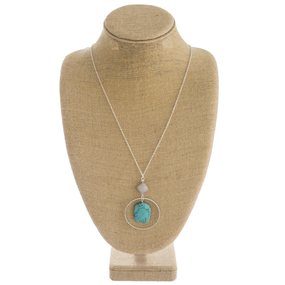 Long cable chain necklace featuring a circular metal pendant with a natural stone inspired center detail and a resin accent. Pendant approximately 3". Approximately 36" in length overall