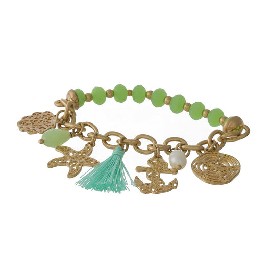 Gold tone and green beaded stretch bracelet displaying sealife and tassel charms